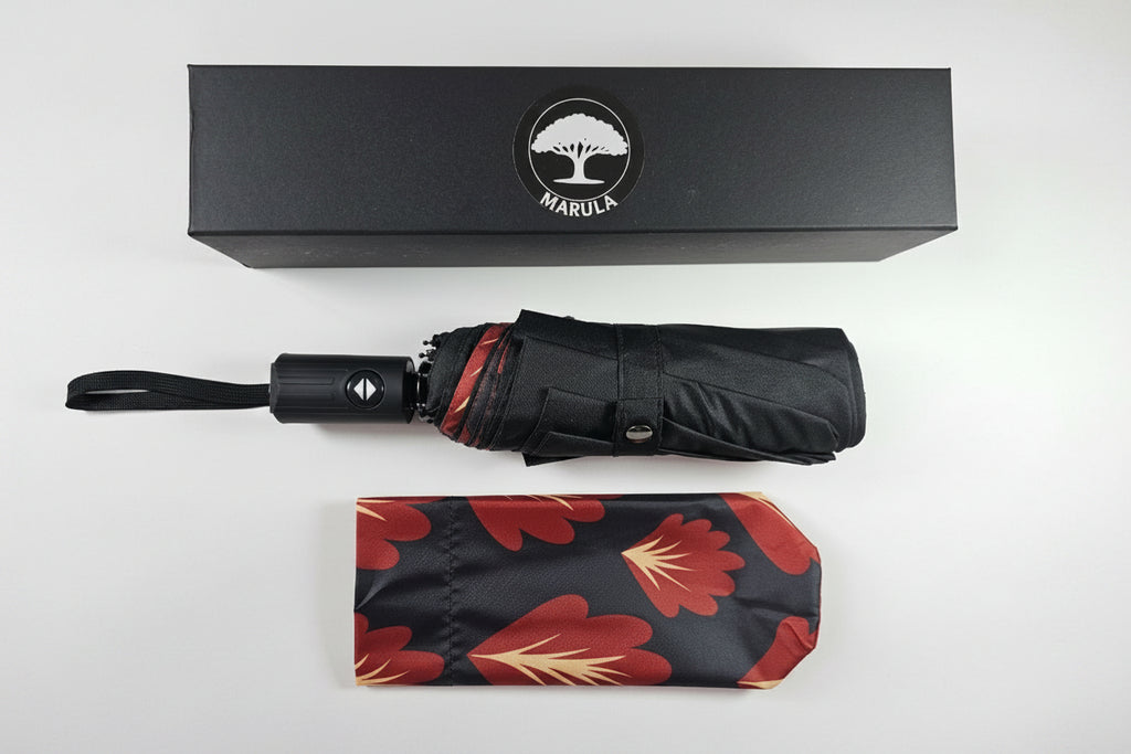 Black umbrella with floral patterned cover and Maruca brand box on a white background